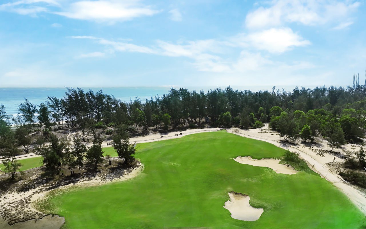 A golf course with sand bunkers and trees  Description automatically generated