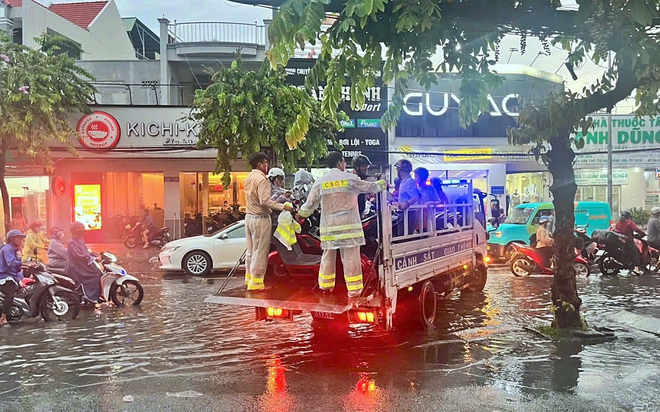 Cảnh s&aacute;t giao th&ocirc;ng Th&agrave;nh phố Hồ Ch&iacute; Minh hỗ trợ người d&acirc;n di chuyển qua đoạn đường ngập s&acirc;u - Ảnh 2.